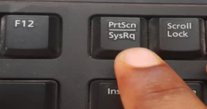 Finger pointing at the Print Screen key on the keyboard. 